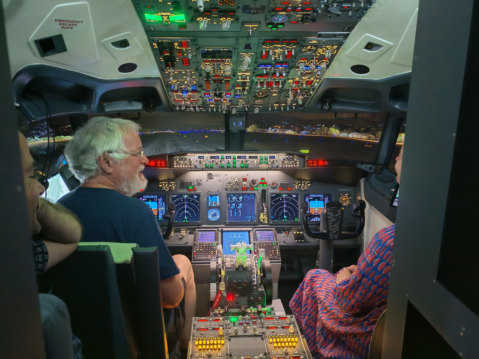 Two guests side by side at the controls, overhead panel ablaze with switches directly above